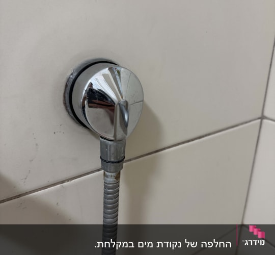 ברז כרום עם צינור גמיש על קיר אריחים